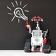 A Lego Mindstorms robot pointing to a chalk drawing of a lightbulb